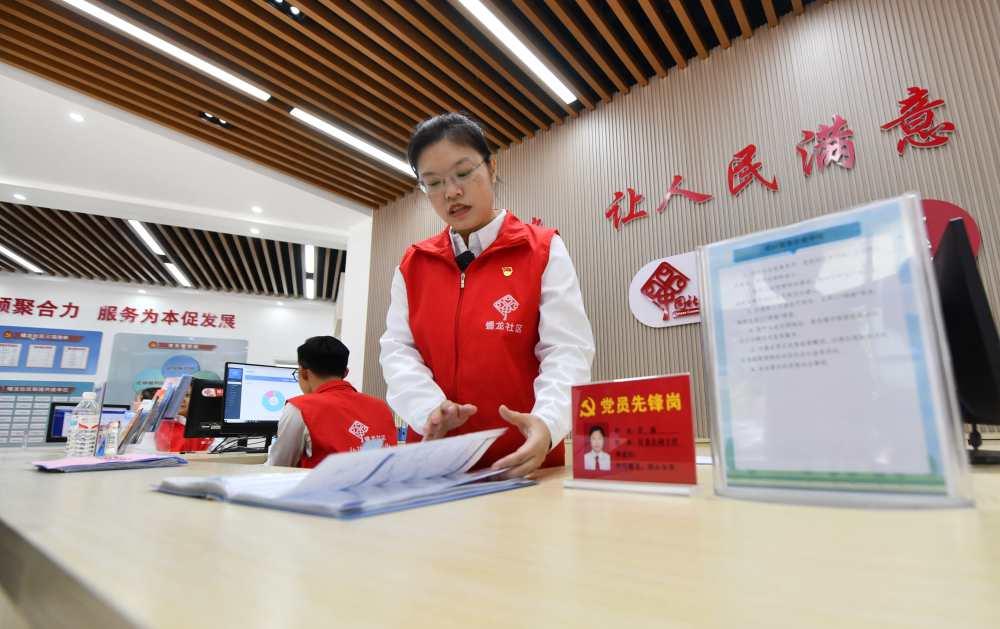 △2023年12月14日,广西南宁市蟠龙社区,工作人员在为居民服务。